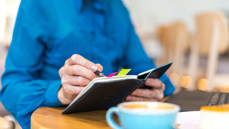 mujer-de-negocios-de-edad-avanzada-que-trabaja-en-la-computadora-portatil-y-escribiendo-en-la-agendac